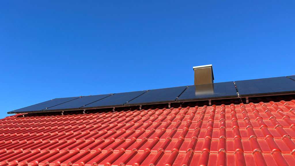 Eine Reihe Photovoltaikpanele montiert auf einem roten Dach